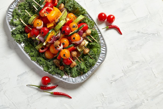 Spiedini vegetariani con erbe secche su spiedini di legno di zucchine pomodoro cipolla funghi su un piatto