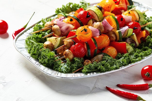 Vegetarian skewers with dry herbs on wooden skewers of zucchini tomato onion mushrooms on a plate