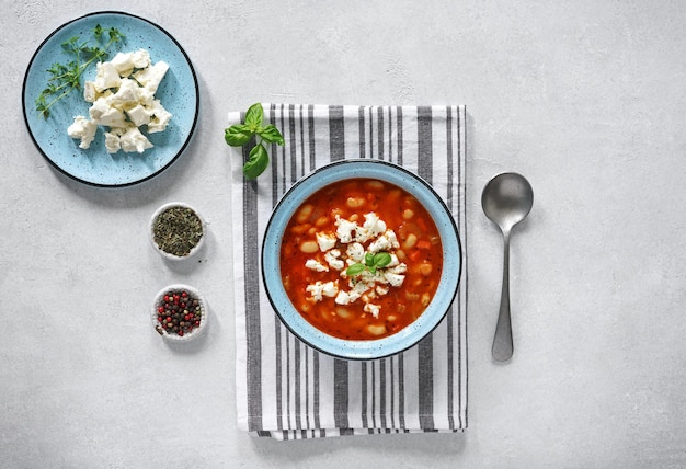 Vegetarian soup with white beans and vegetables on light background top view