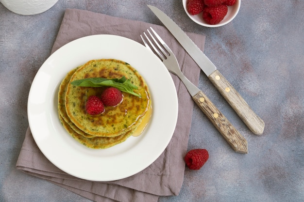 Vegetarian spinach pancakes with raspberries and honey.