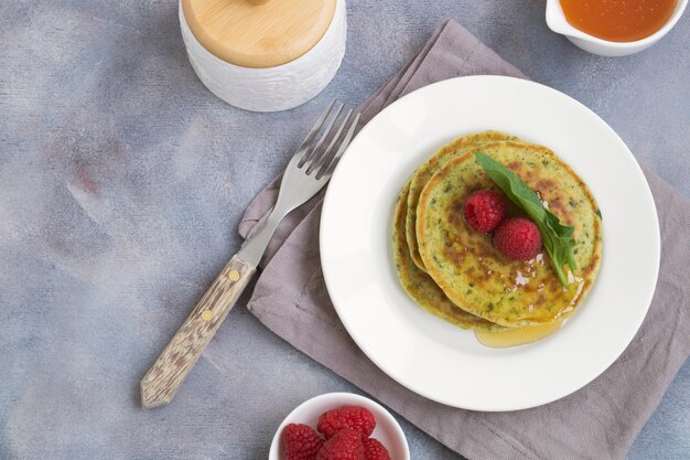 Vegetarian spinach pancakes with raspberries and honey.