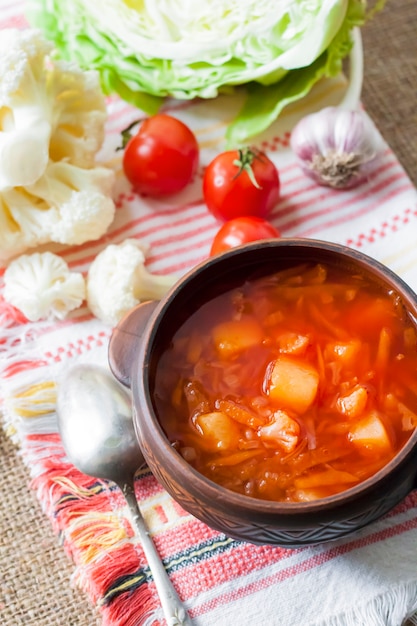 Zuppa vegetariana di pomodoro con cavolo cappuccio e cavolfiore in una ciotola rustica di ceramica