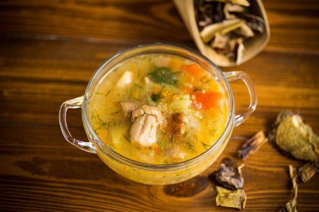 木のテーブルの上のガラスのボウルにポルチーニ茸が入ったベジタリアン野菜スープ