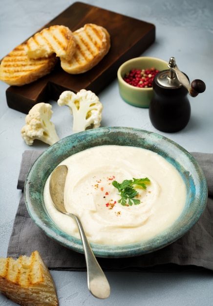 Vegetarian white soup cream from cauliflower in a vintage ceramic plate