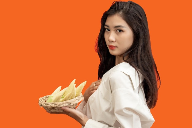 Vegetarisch concept Gezonde vrouw met mand met babymaïs geïsoleerd oranje background