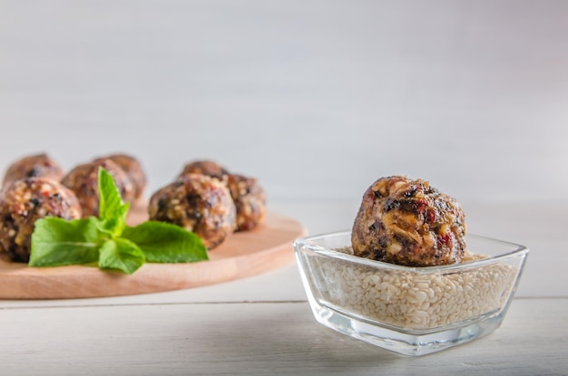 Vegetarisch eten, zelfgemaakte energieballen van walnoten, dadels, pruimen, veenbessen en honing met sesam op witte achtergrond