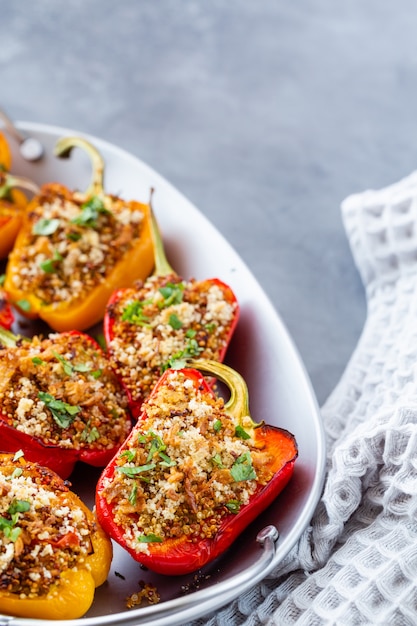 Vegetarisch gerecht met paprika gevuld met quinoa, ui en tomaat, bestrooid met walnoten