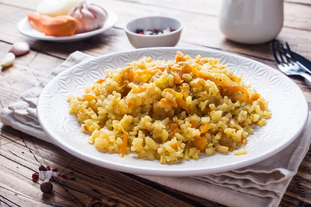 Vegetarisch Oosters pilau met rijst en groenten op een houten tafel.