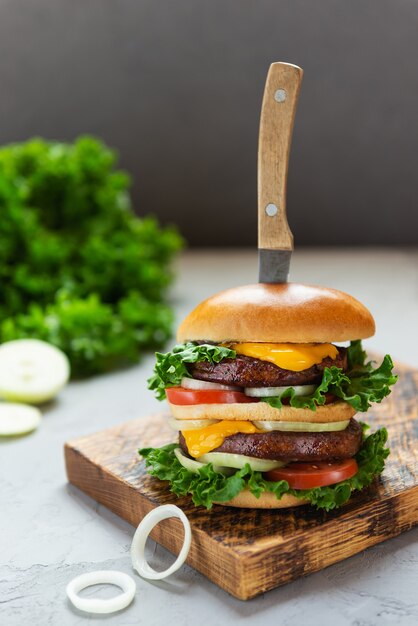 Vegetarische cheeseburger met een mes op een houten plank