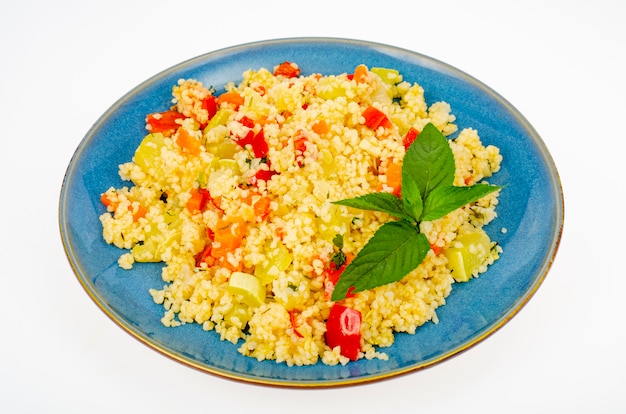 Vegetarische couscous pilaf met groenten op blauw bord. Studiofoto.