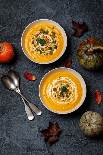 Vegetarische de roomsoep van de de herfstpompoen met zaden in witte kommen. Pompoensoep