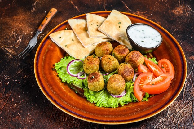 Vegetarische falafel met pitabroodje, verse groenten en saus op een bord