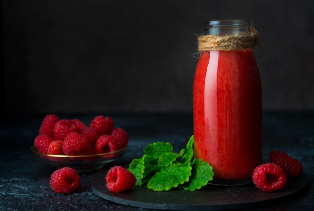 Vegetarische frambozen smoothie in een glazen fles op een donkere achtergrond, close-up