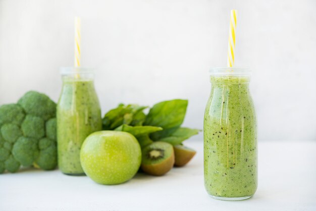 Vegetarische groene smoothie met groenten en fruit in glazen flessen, selectieve aandacht
