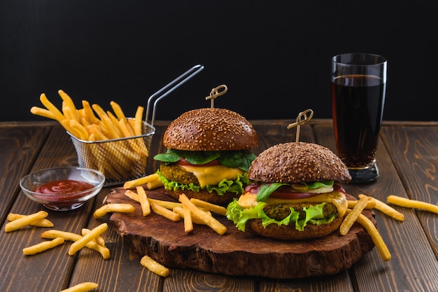 Vegetarische Hamburger met friet en drank op houten tafel