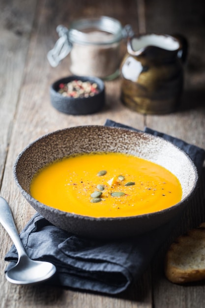 Vegetarische herfstpompoenroomsoep met zaden op houten ondergrond