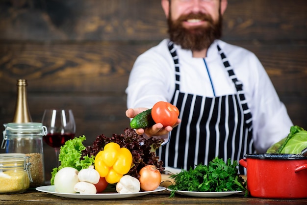 Vegetarische levensstijl Chef bereiden heerlijke maaltijd houten achtergrond Verliefd op gezond voedsel Honger en eetlust Gezond vegetarisch recept Man bebaarde hipster dragen schort koken gezond voedsel