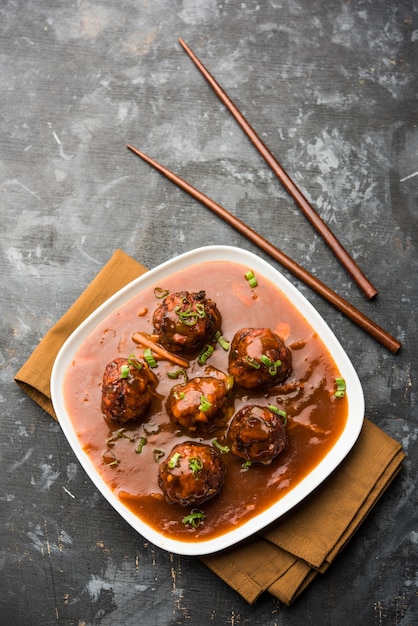 Vegetarische of kip Manchurian met jus - Populair Indiaas eten geserveerd in een kom met eetstokje