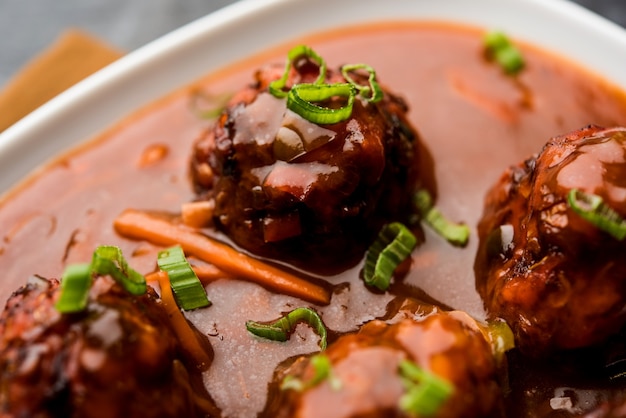 Vegetarische of kip Manchurian met jus - Populair Indiaas eten geserveerd in een kom met eetstokje