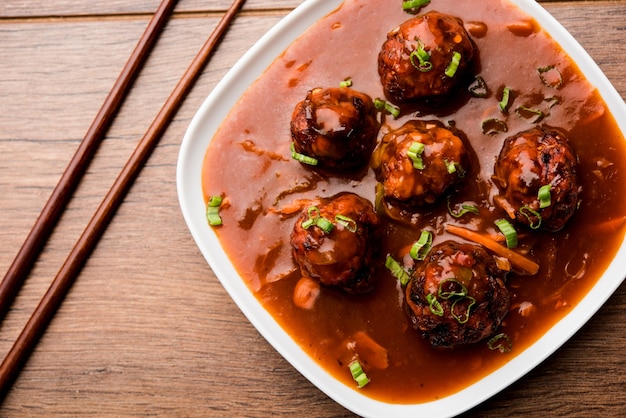 Vegetarische of kip Manchurian met jus - Populair Indiaas eten geserveerd in een kom met eetstokje