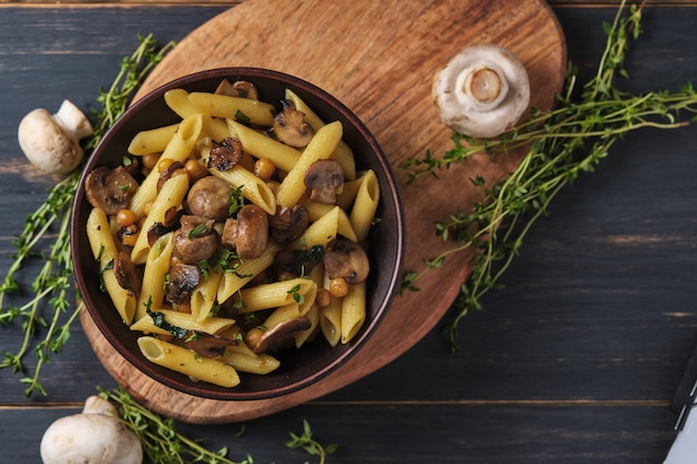 Vegetarische pasta met champignons, kikkererwten, spinazie, specerijen en kruiden. Italiaanse pasta in een kom op een oude houten tafel. Bovenaanzicht.