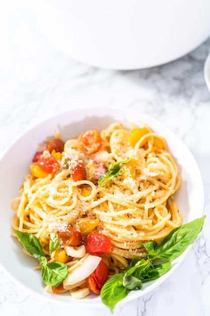 Vegetarische pasta met kerstomaatjes en verse basilicum op een witte plaat.