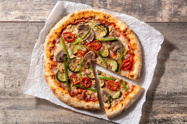 Vegetarische pizza met courgette, tomaat, paprika en champignons op houten tafel