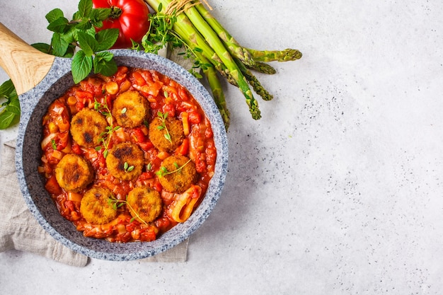 Vegetarische plantaardige gehaktballetjes in tomatensaus in een koekenpan.