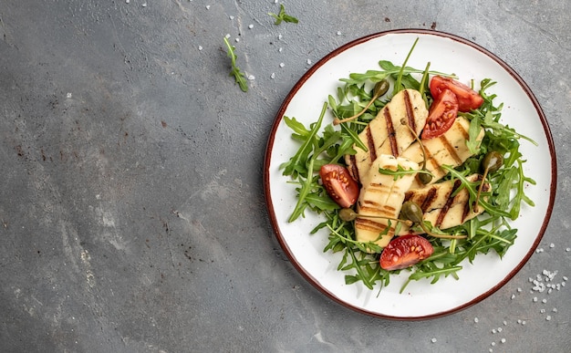 Vegetarische salade met gebakken halloumi en tomaten close-up keto ketogeen dieet Heerlijk ontbijt of snack Schoon eten dieet veganistisch voedsel concept bovenaanzicht