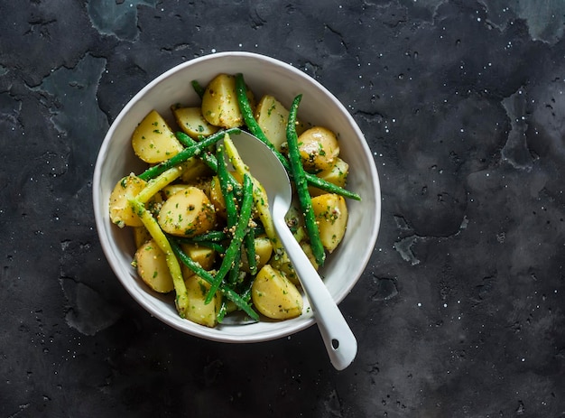 Vegetarische salade met nieuwe aardappelen, sperziebonen en citroen-mosterddressing op een donkere achtergrond bovenaanzicht