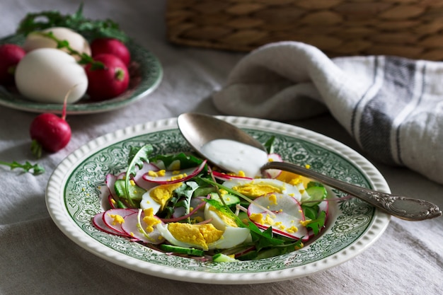 Vegetarische salade met paardenbloembladeren, groenten, ei en zure room. Rustieke stijl.