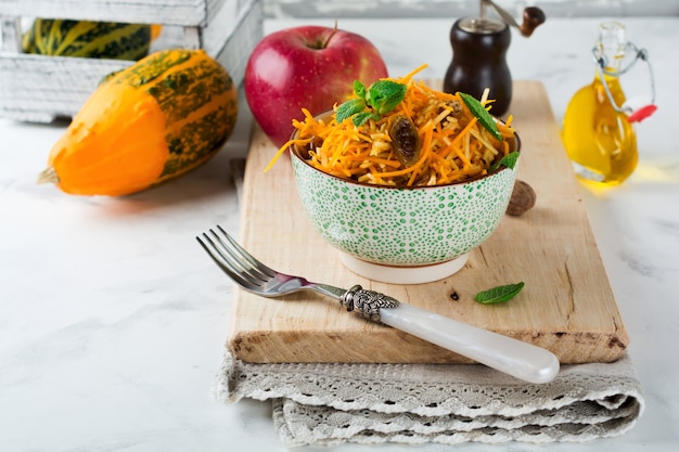 Vegetarische salade met pompoen, appels en rozijnen op een lichte ondergrond