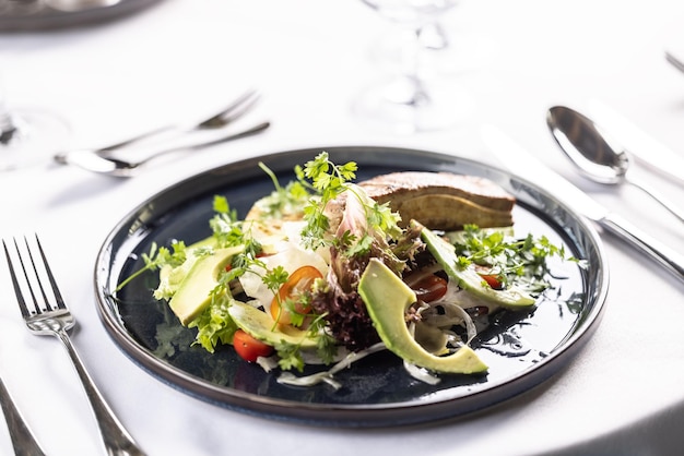 Vegetarische salade met tofu laat tomaten en avocado op een donkere plaat