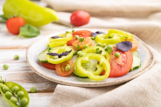 Vegetarische salade van groene erwten, tomaten, peper en basilicum op witte houten achtergrond Zijaanzicht selectieve focus