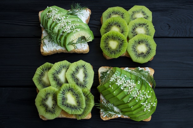 Vegetarische sandwiches met avocado en kiwi op de zwarte houten achtergrond