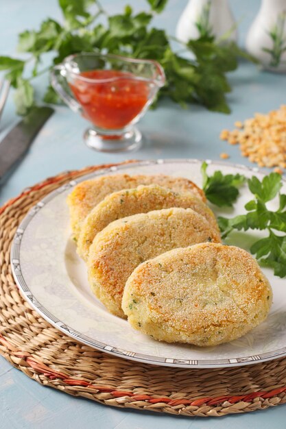 Vegetarische schnitzels van erwten en griesmeel in een bord en chilisaus op blauwe achtergrond