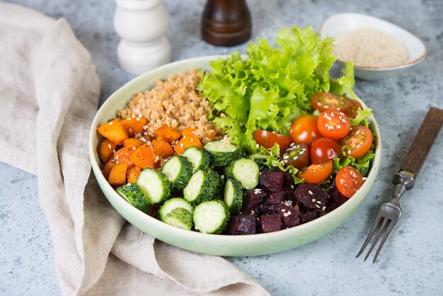 Vegetarische schotel een kom van gezonde quinoa met verse en gebakken groenten op een grijze betonnen achtergrond. Close-up, selectieve focuse