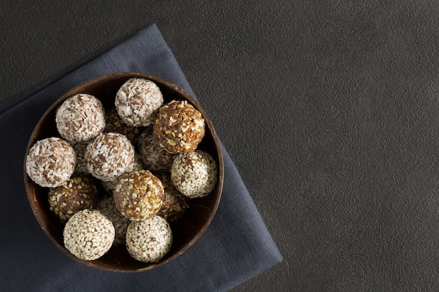 Vegetarische snoep energie ballen in de houten kom op servet plat leggen op donkere achtergrond met kopie ruimte