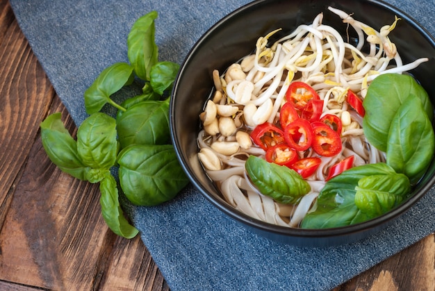 Vegetarische soep pho in Vietnamese stijl met garnituren en eetstokjes