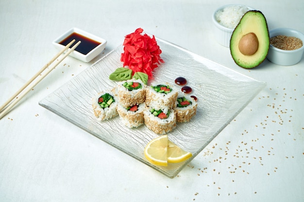 Vegetarische sushi rolt met groenten en sesamzaadjes op een witte plaat in een compositie met ingrediënten