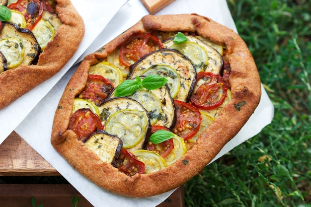 Vegetarische taarten met groenten en kruiden op een krukje tegen een achtergrond van groen gras.