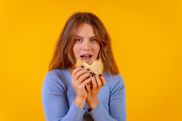 Vegetarische vrouw bijt een broodje op een gele achtergrond gezond vegetarisch eten