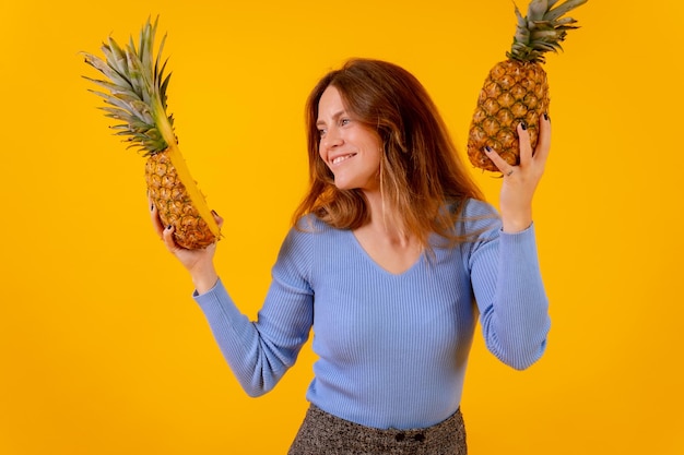 Vegetarische vrouw met een ananas in zonnebril dansen en gelukkig gezond leven gele achtergrond