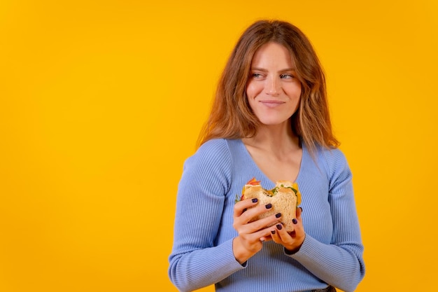 Vegetarische vrouw met een broodje op een gele achtergrond gezond vegetarisch eten