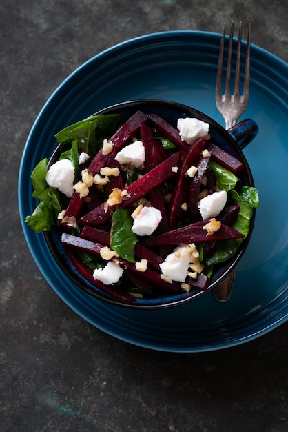 Insalata vegetariana di barbabietole con spinaci, formaggio di capra e noci varie in una ciotola di ceramica. dieta, sano, spuntino, concetto di pranzo del pasto. su sfondo rustico. vista dall'alto. lay piatto.