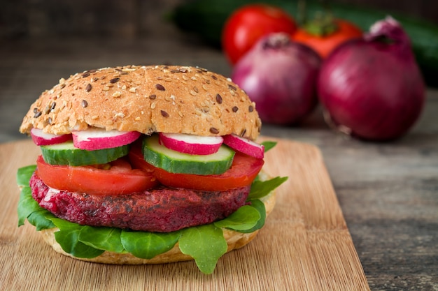 Veggie bietenburger met veldsla, tomaat, radijs en komkommer op rustieke houten tafel