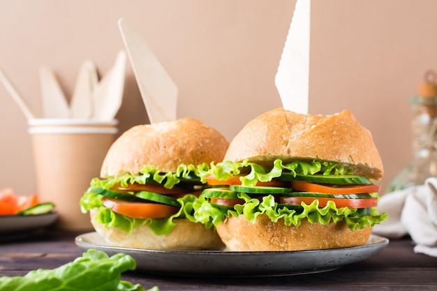 Veggie burger with fresh vegetables and lettuce in a bun with\
sesame seeds on a plate on the table vegetarian food closeup