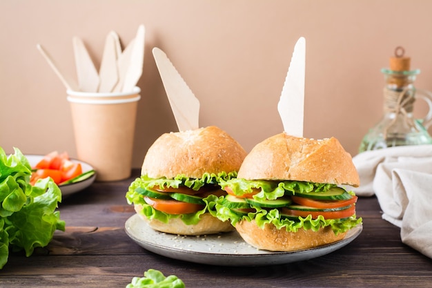 Veggie burger with fresh vegetables and lettuce in a bun with\
sesame seeds on a plate on the table vegetarian food