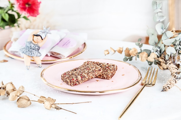 Veggie healthy Bars with Figs served on rose plate above white background. Close up horizontal food photo. Gluten free, healthy dessert. Vegan food and sweets. Homemade snack. Copy space