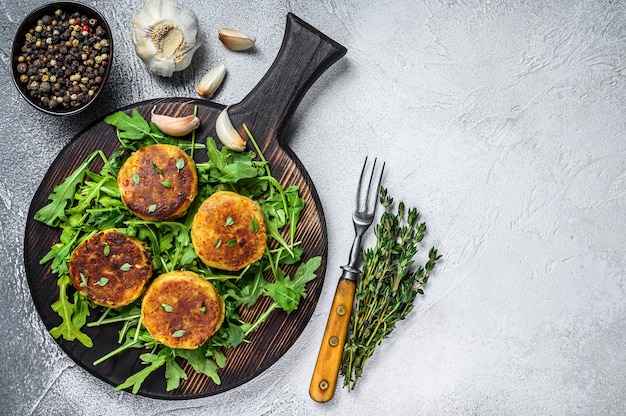 Veggie patty cutlet with lentils, vegetables and arugula. White table. Top view. Copy space.
